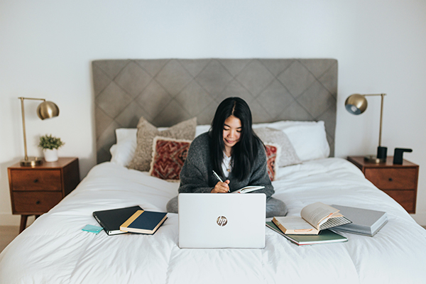 Photo of a woman working from her bedroom using laptop