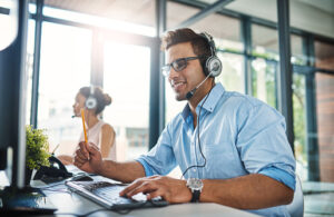 young man in customer service at computer with headphones
